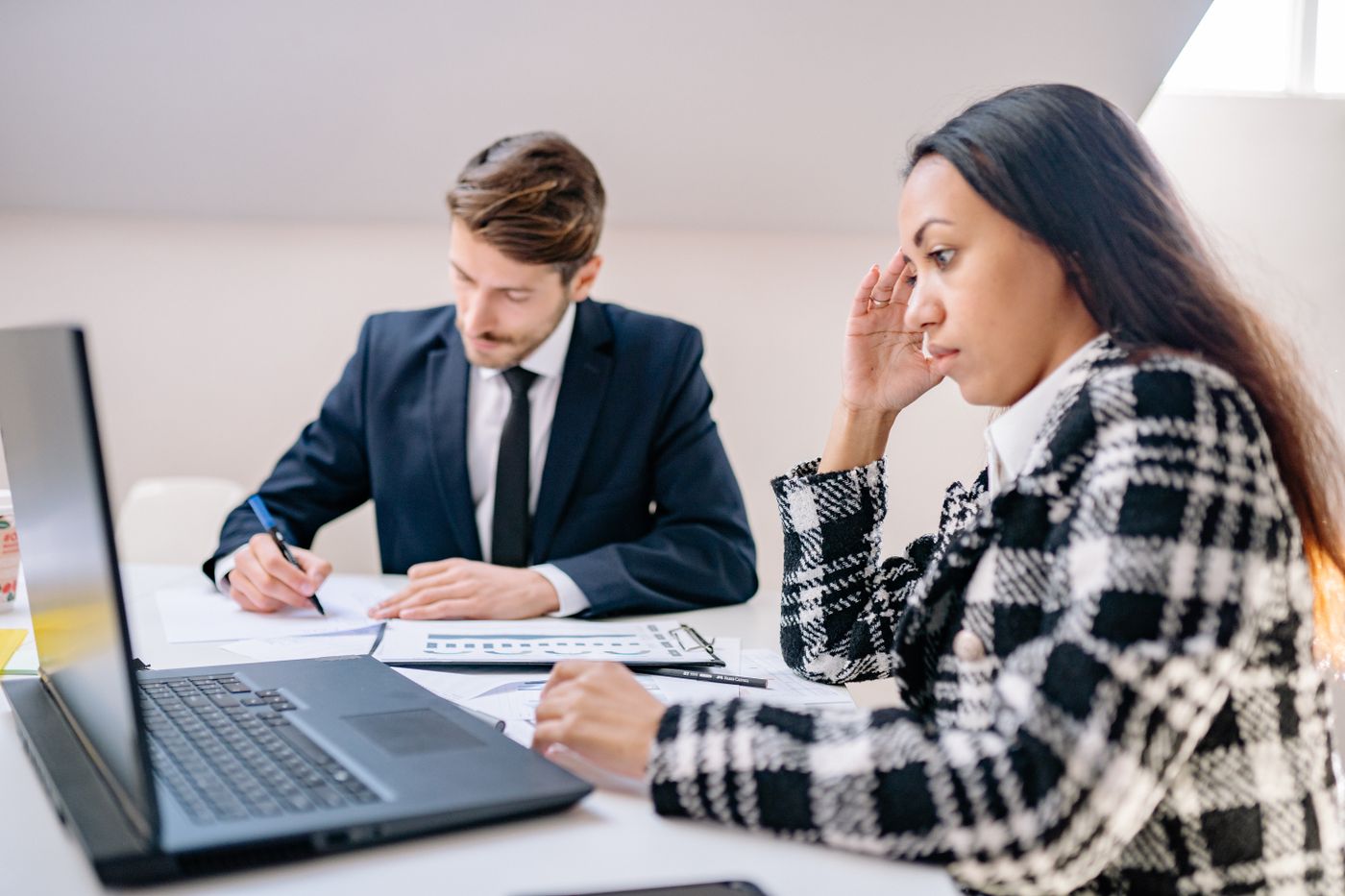 Two business professionals working together in an office, focusing on a project.