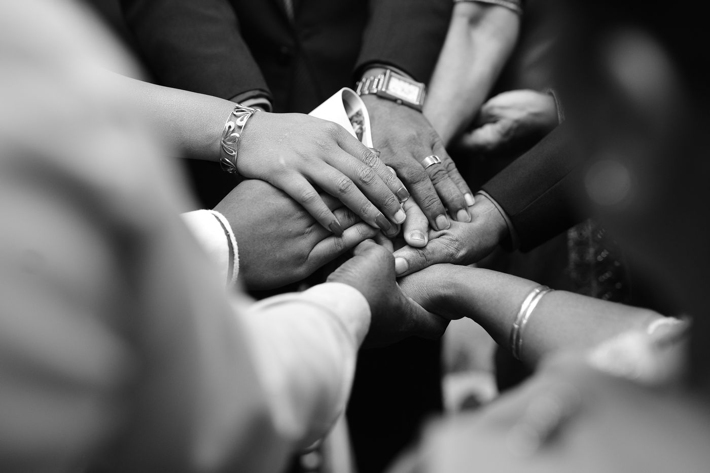 A close-up black and white photo of diverse hands united in prayer, symbolizing spiritual unity.