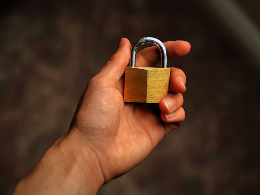 Hand holding a brass padlock, symbolizing security and protection