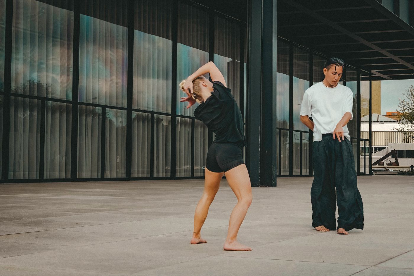 Two dancers performing contemporary dance outside a Berlin gallery.